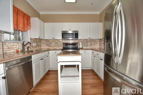 A kitchen with white cabinets and a stainless steel refrigerator.