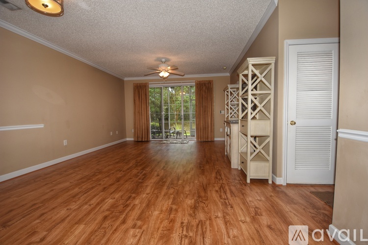 A spacious room with wooden flooring and a sliding glass door leading to a patio.
