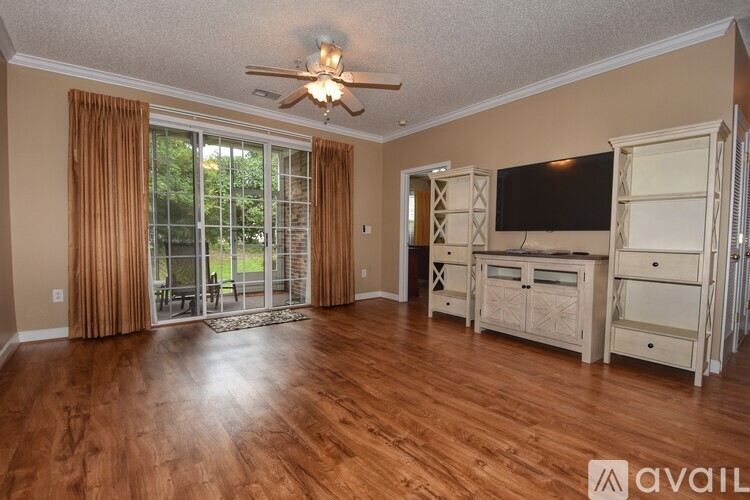 A spacious living room with wood flooring and a ceiling fan.
