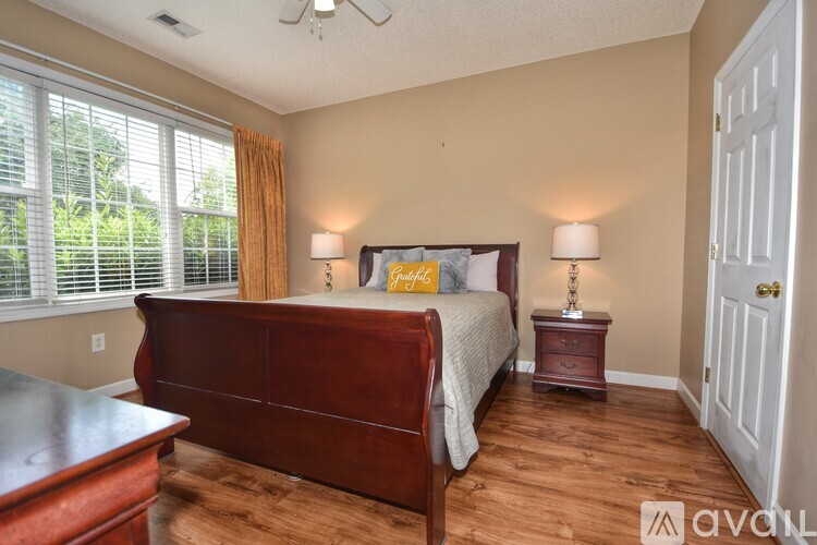 A bedroom with a bed, nightstand, and window with blinds.