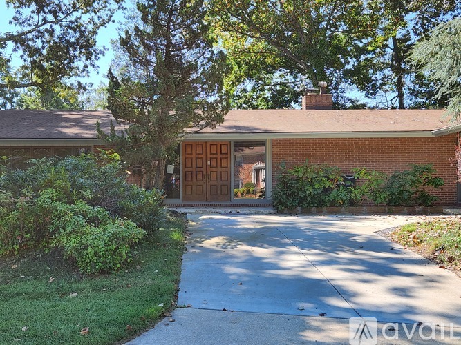 A house with a brown garage door is surrounded by greenery.
