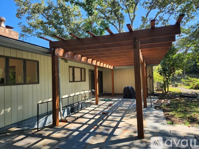 A wooden pergola is attached to a building.