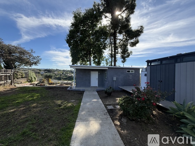 A modern house with a concrete pathway leading to the front door.