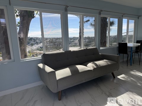 A couch is in a sunny room with a view of the outdoors.