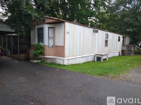 A mobile home with the number 12 on the side is surrounded by trees.