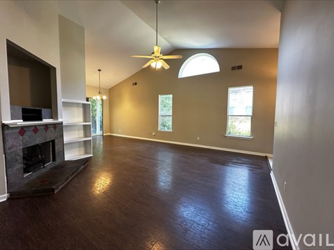 A spacious living room with a fireplace and a ceiling fan.