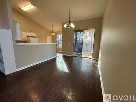 A spacious room with wooden floors and a large window.