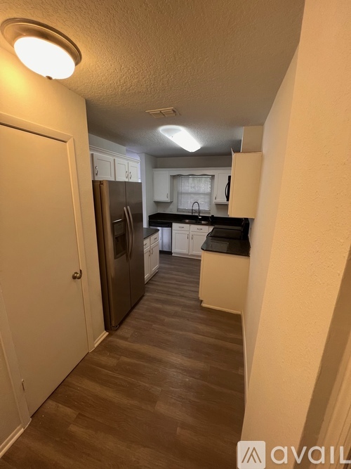 A kitchen with a refrigerator, sink, and cabinets.