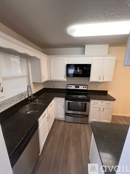 A kitchen with black countertops and white cabinets.