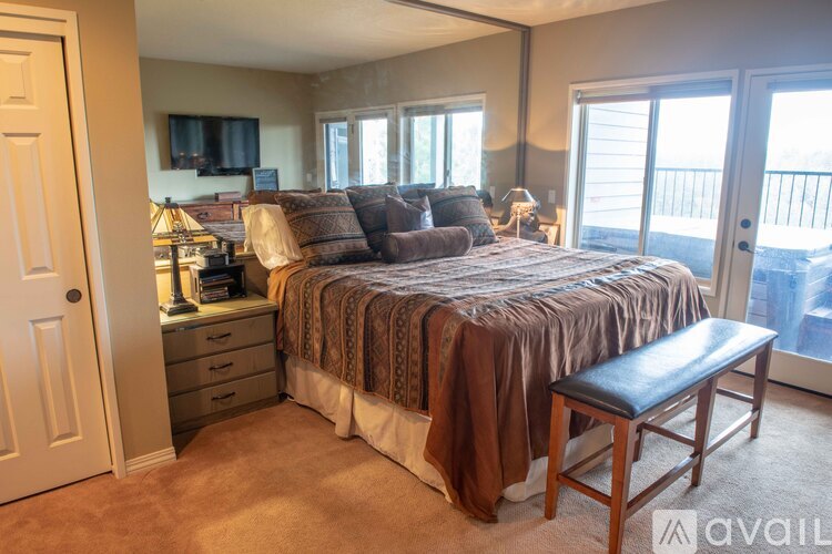 A bedroom with a bed, a couch, a chair, and a TV.