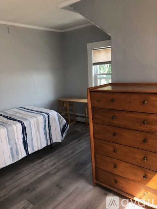 A bedroom with a bed and a wooden dresser.
