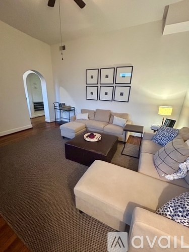 A living room with a couch, a coffee table, and a carpet.