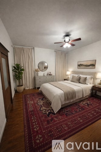 A bedroom with a large bed and a red rug on the floor.