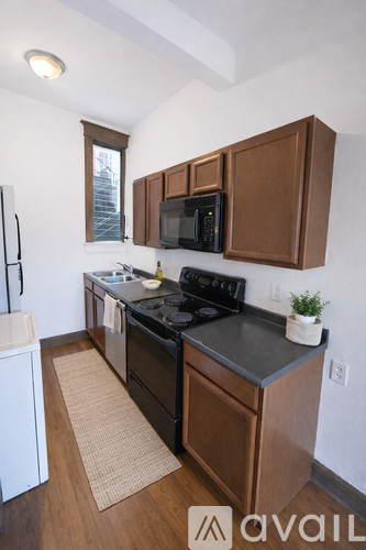 A kitchen with brown cabinets and black appliances.