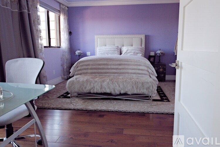 A bedroom with a white bed and a white chair.