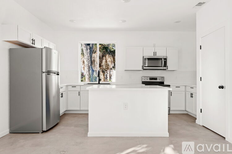 A modern kitchen with a refrigerator, microwave, and oven.