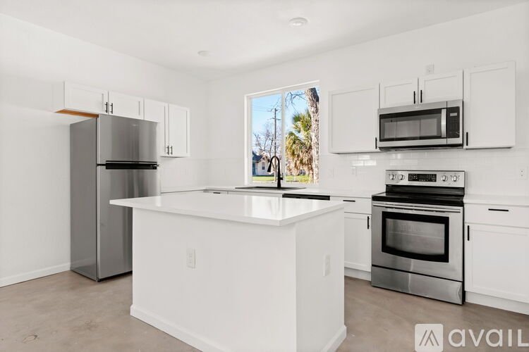 A kitchen with white cabinets and appliances, a window with a view of trees outside, and a countertop.
