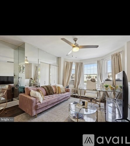 A living room with a pink couch and a ceiling fan.