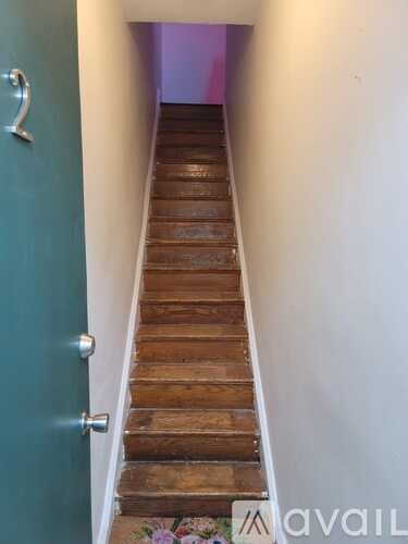 A staircase with a teal door on the left.