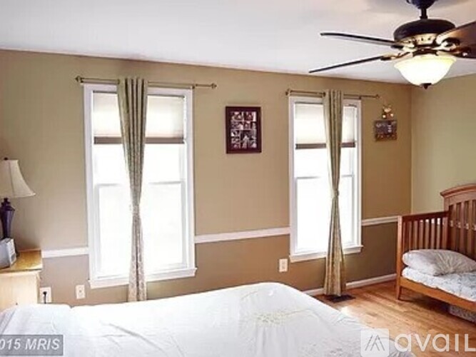 A bedroom with a white bed and a ceiling fan.