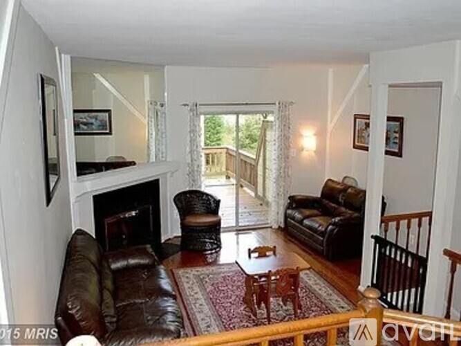 A living room with a brown leather couch and a fireplace.