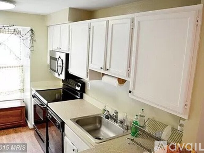A kitchen with white cabinets and black appliances.