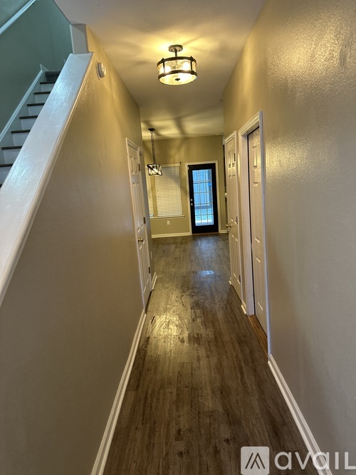 A hallway with wood floors and white walls.