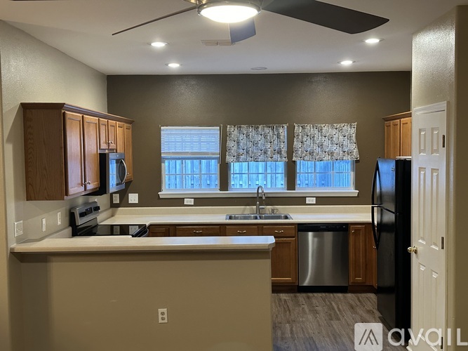 A kitchen with a stainless steel dishwasher and a black refrigerator.