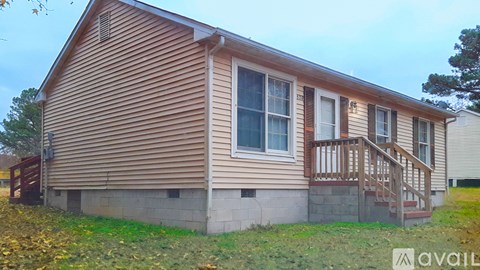 A house with a brown wooden exterior and a white window is available for rent.