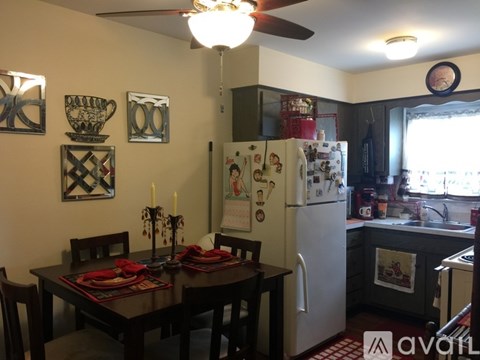 A kitchen with a table set for two and a fridge with magnets.