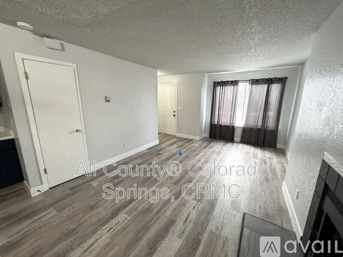 A room with wood flooring and a window with curtains.
