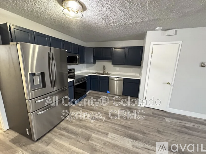 A kitchen with a stainless steel refrigerator and black cabinets.