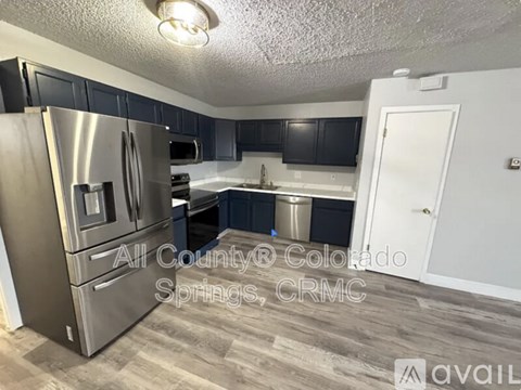 A kitchen with a stainless steel refrigerator and black cabinets.