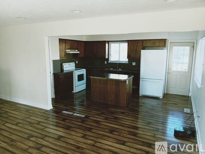 A kitchen with wooden floors and white appliances.
