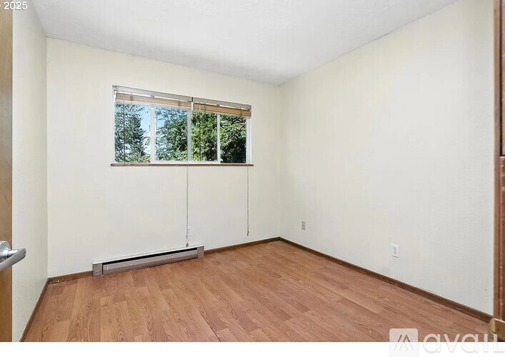A room with wooden flooring and a window with blinds.