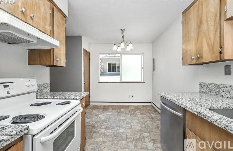 A kitchen with a white stove top oven and a marble counter top.