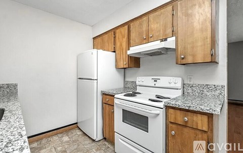 A kitchen with a white refrigerator, white stove, and wooden cabinets.