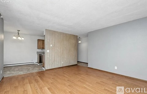 A spacious room with wooden flooring and a fireplace.
