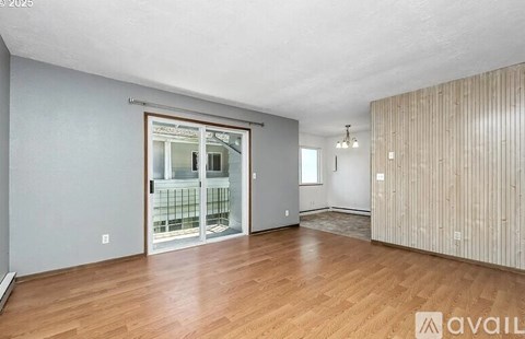 A room with wooden floors and a sliding glass door leading to a balcony.