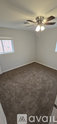 A room with a ceiling fan and carpeted floor.