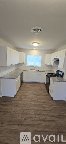 A kitchen with white cabinets and a wooden floor.