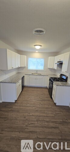 A kitchen with white cabinets and a wooden floor.