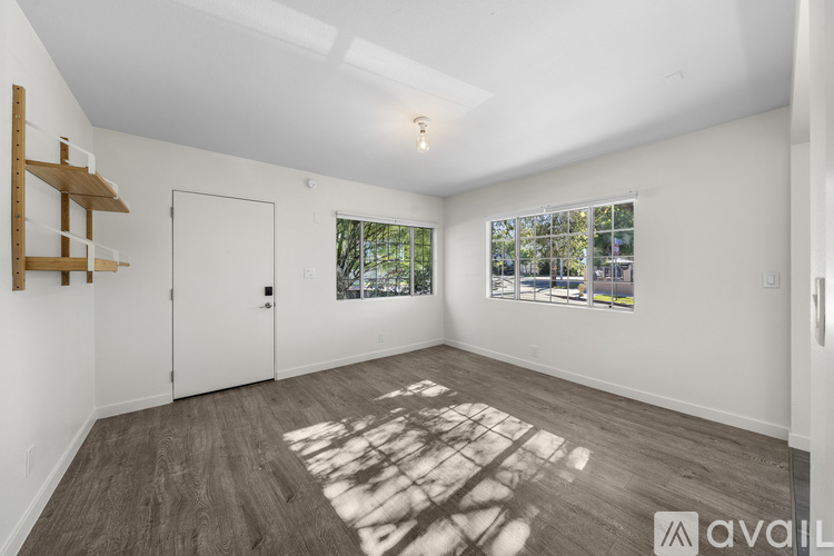A room with a white door and a window with a view of trees and a building outside.