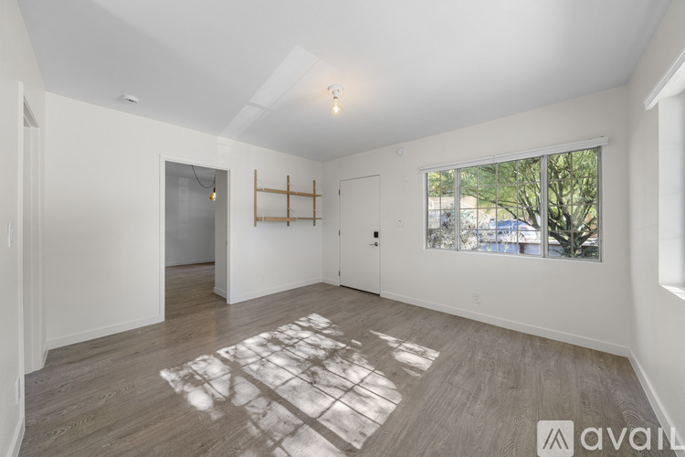A spacious room with wooden flooring and white walls.