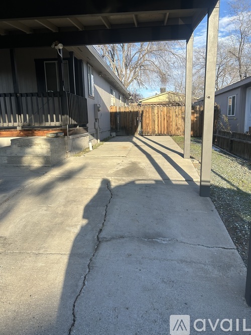 A concrete walkway leads to a house with a black railing.