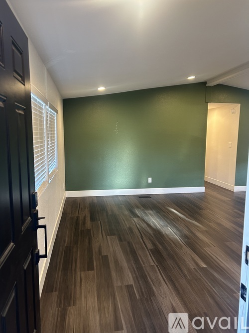 A room with dark wood flooring and green walls.