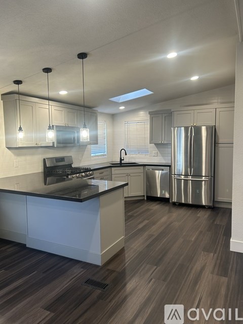 A modern kitchen with a stainless steel refrigerator and a black countertop.