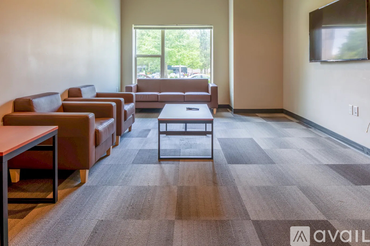 A waiting room with brown leather chairs and a flat screen TV mounted on the wall.