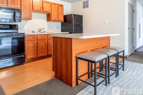 A kitchen with wooden cabinets and a black refrigerator.
