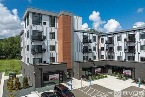 A modern apartment complex with a parking lot in front.